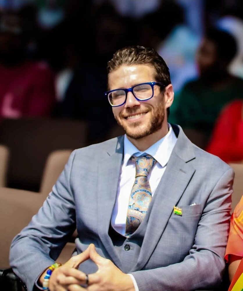 Kevin Frey, Founder and CEO of Just Keep Going Inc, seated at a sports event in a grey suit