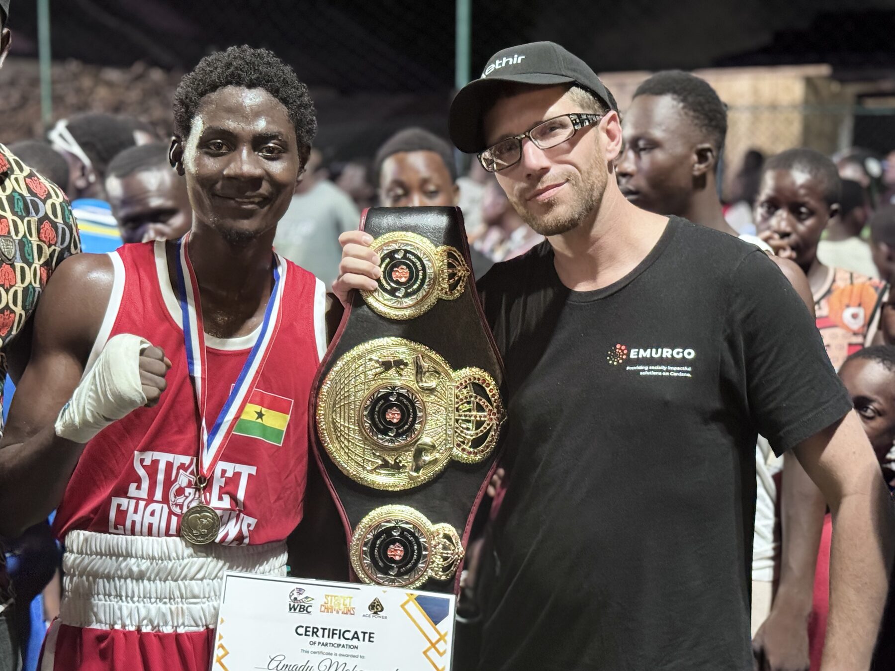 Kevin Frey with a boxer holding a championship belt at a grassroots event in Accra